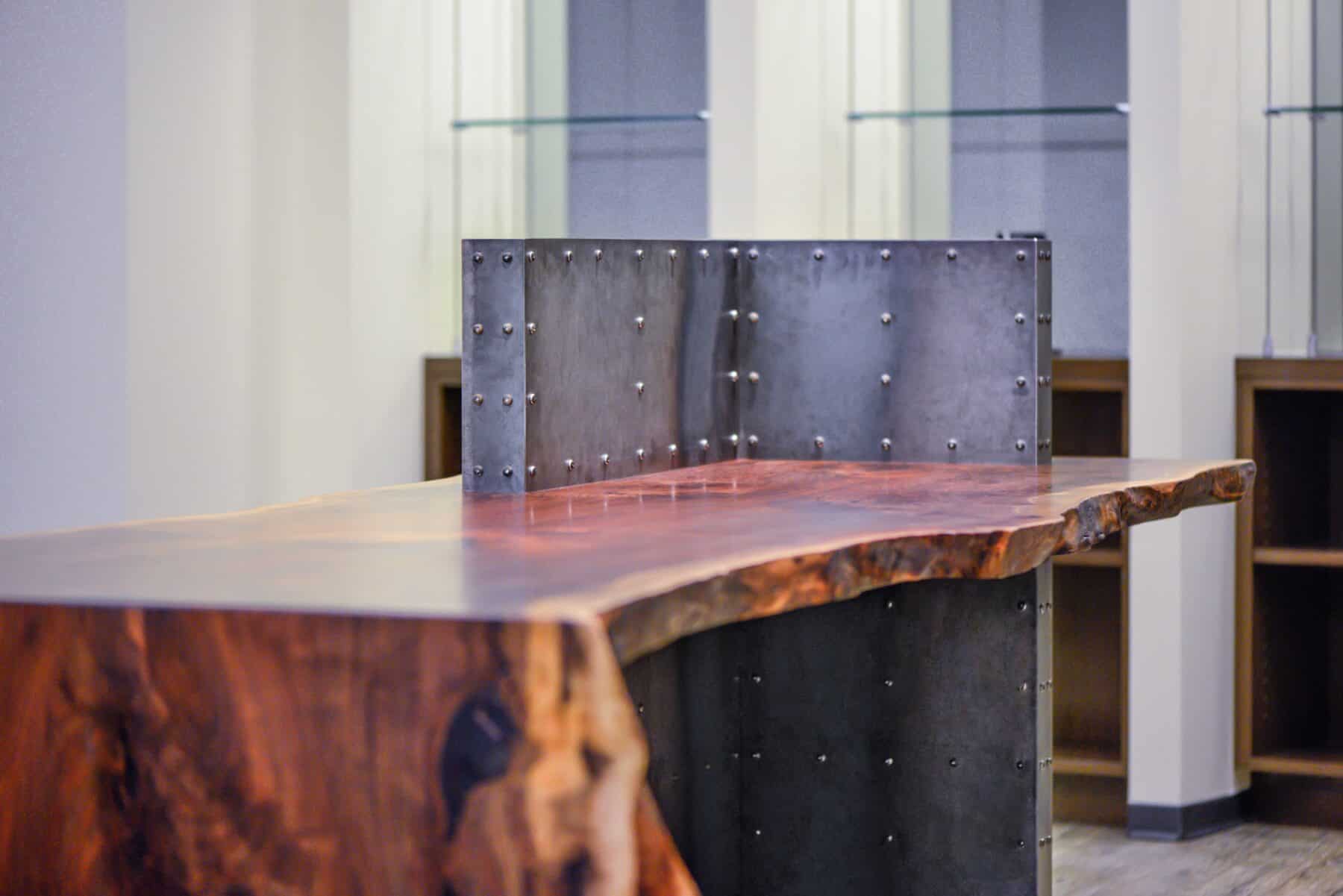 Custom Live Edge Walnut Reception Desk with Distressed Metal Base with Rivets from Construction Specialty Projects by Commercial Builder & General Contractor Structural Enterprises