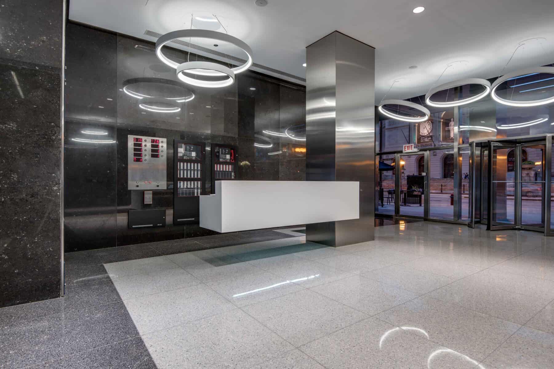 Michigan Avenue Lobby Remodel with White Floating Reception Desk and Suspended Circular Lights by Commercial Builder & General Contractor Structural Enterprises